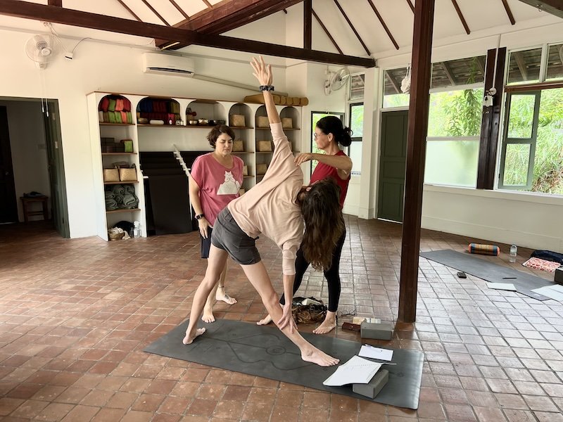 Photo of two students and mentoring practicing alignment during yoga teacher mentoring programme Luang Prabang